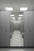 Full-length mirror panel installed between two phenolic locker columns reflecting the locker room aisle